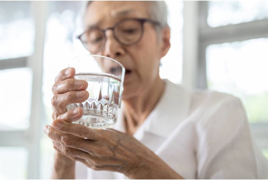 Senior woman drinking water with shaking hands